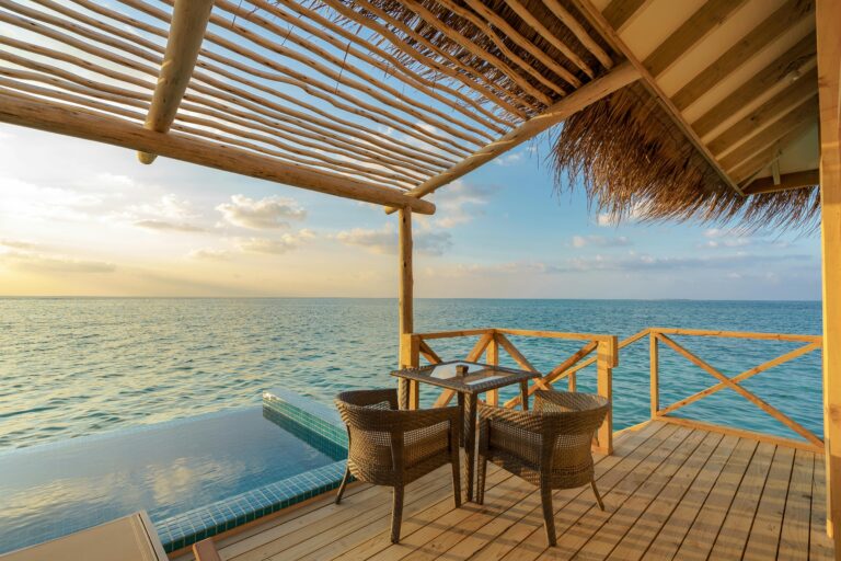 Overwater Bungalows at Sunset - Thatched-roof villas stretch across Bora Bora's turquoise lagoon as the sun paints the sky in tropical hues